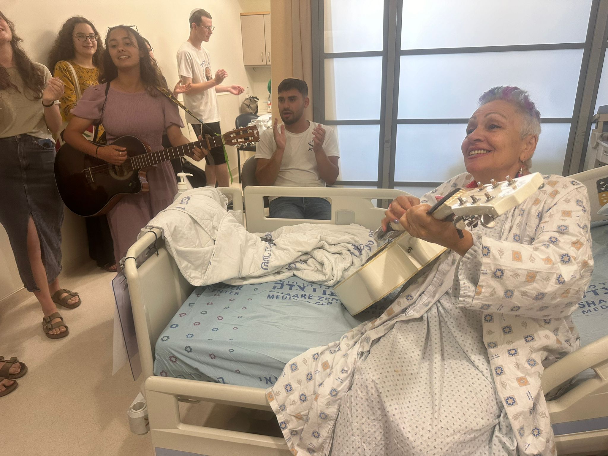 חנה אהרוני מנגנת ממיטת בית החולים לצד משפחה וחברים